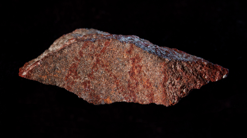 The red marks on this flake represent the oldest known drawing in the archaeological record, according to new research.